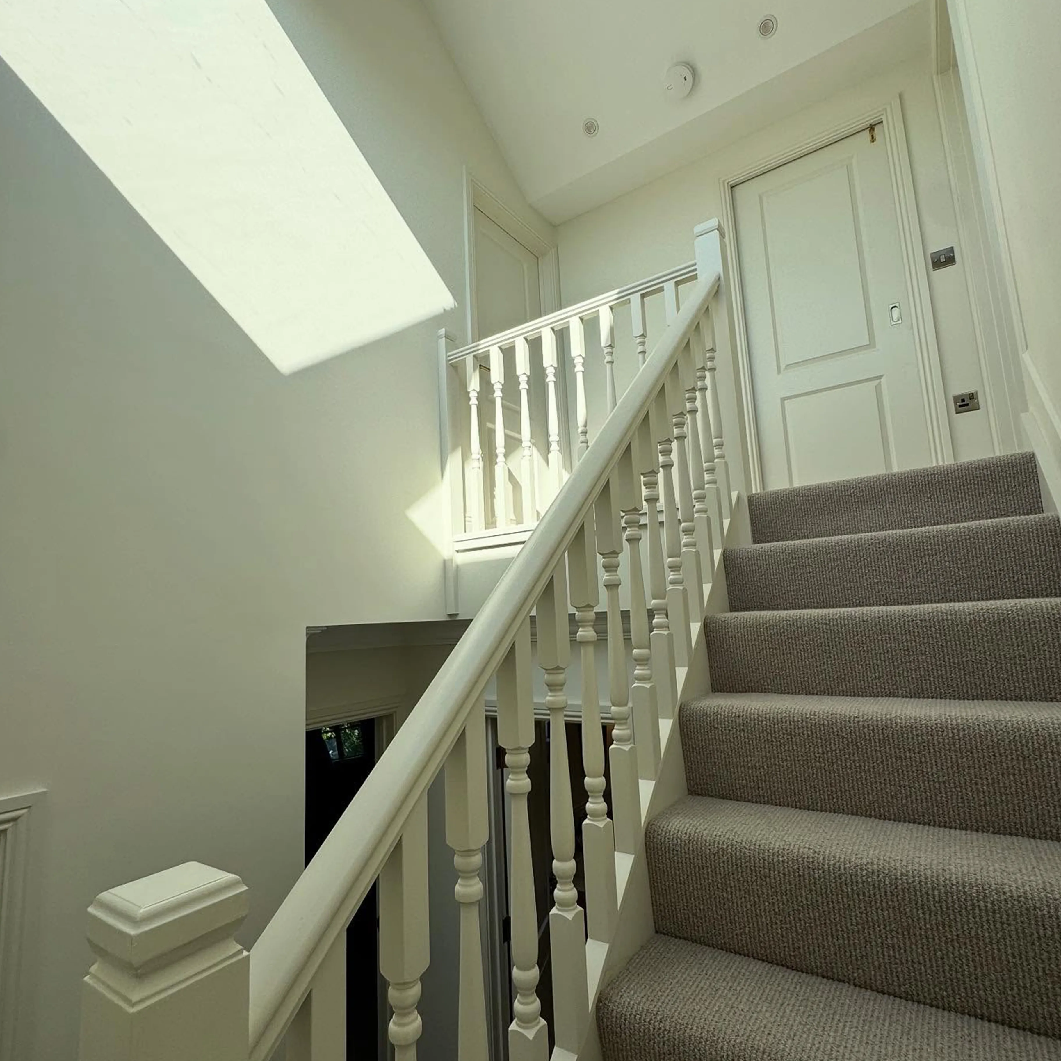 A white staircase with a skylight above it.