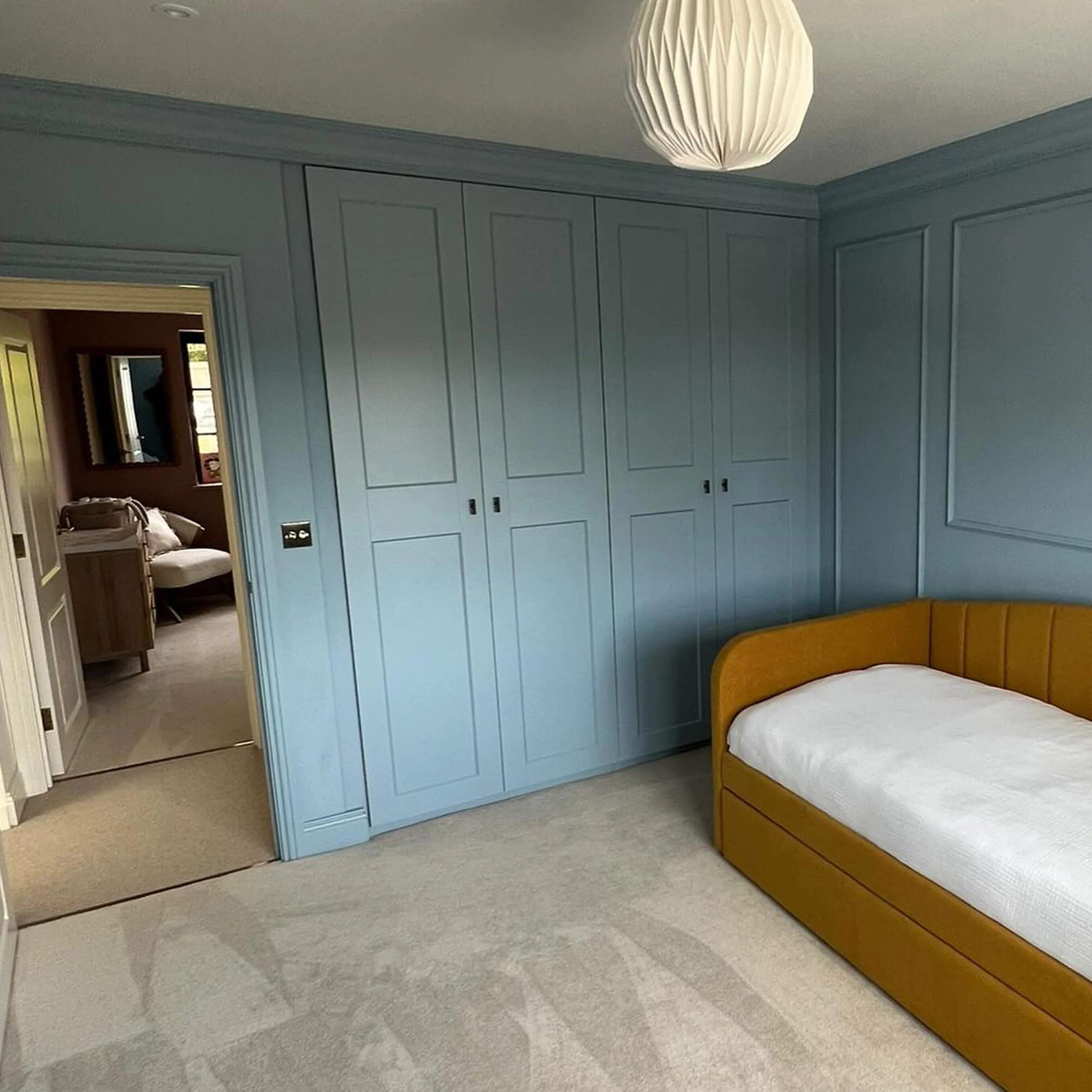 A bedroom with blue walls and a white bed.