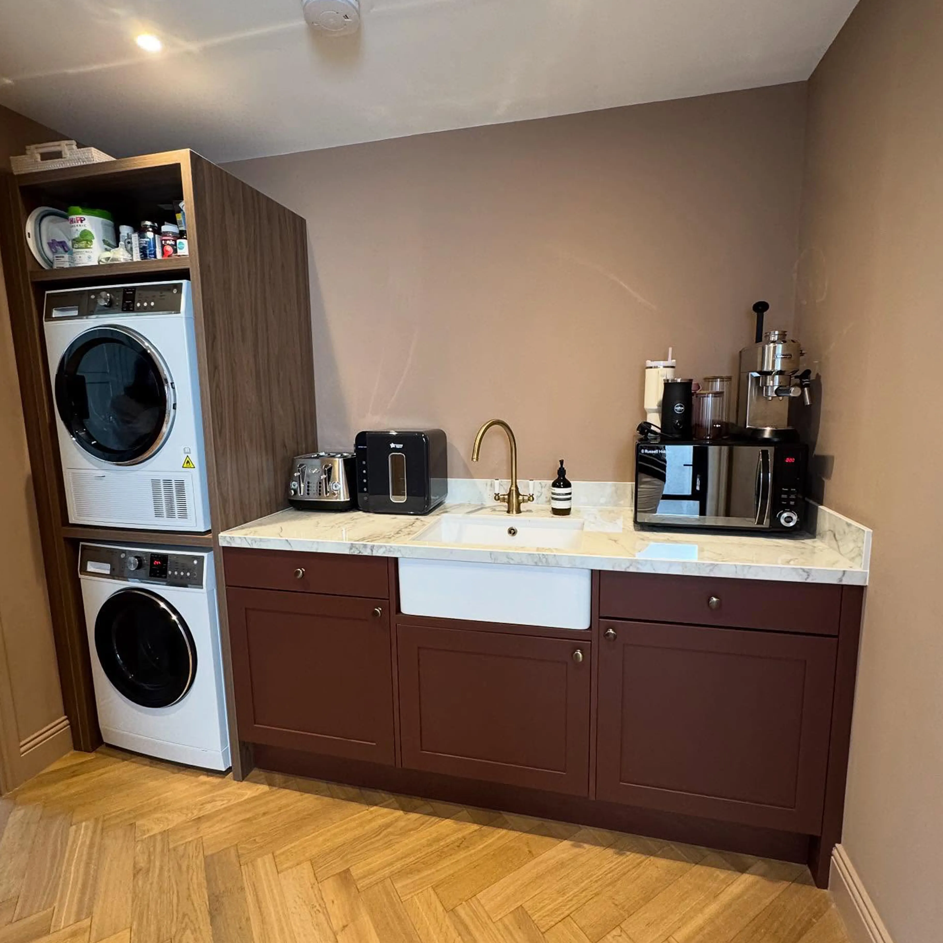A kitchen with a washer, dryer and coffee maker.